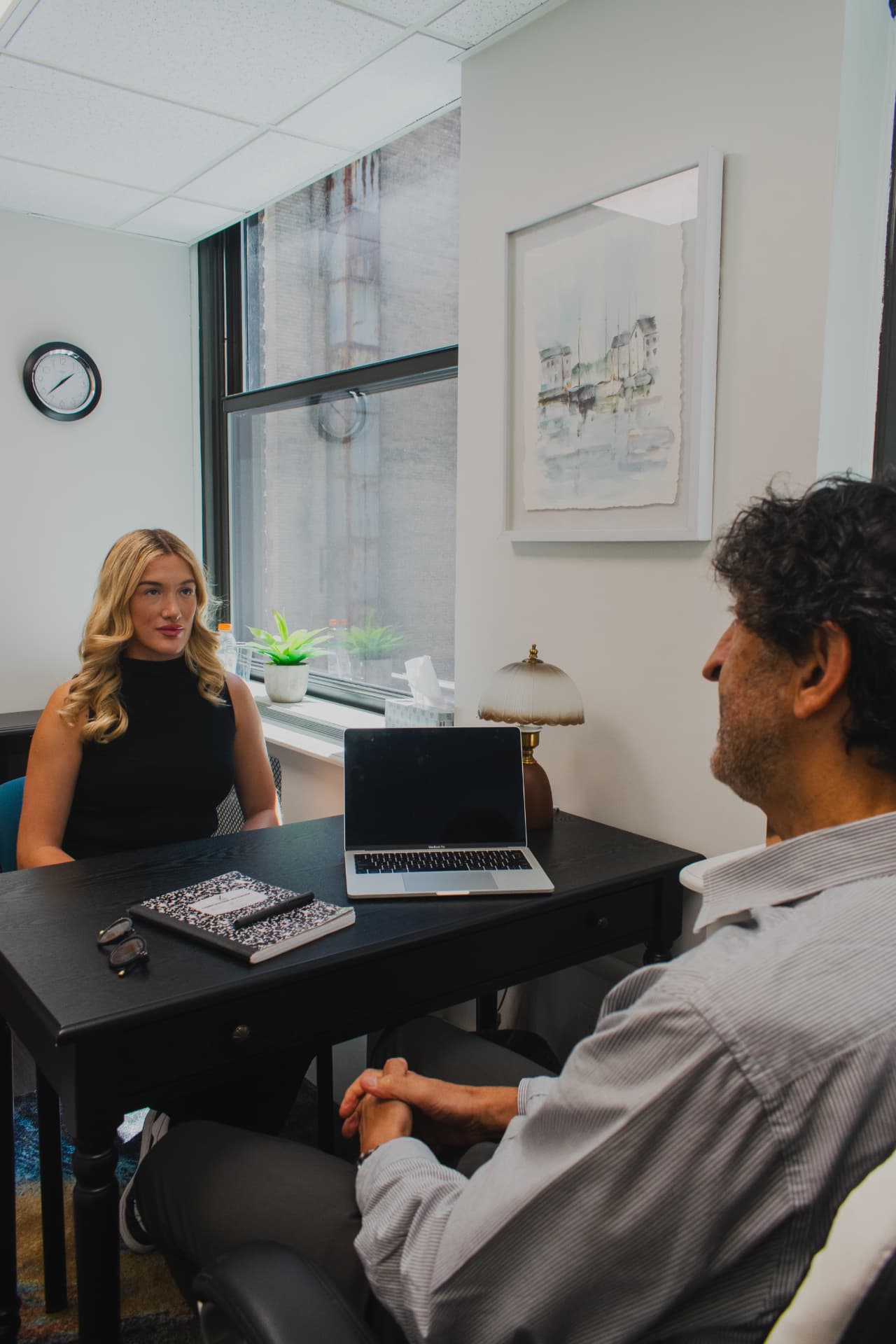 Client and clinician talking across a desk in a bright Manhattan therapy office