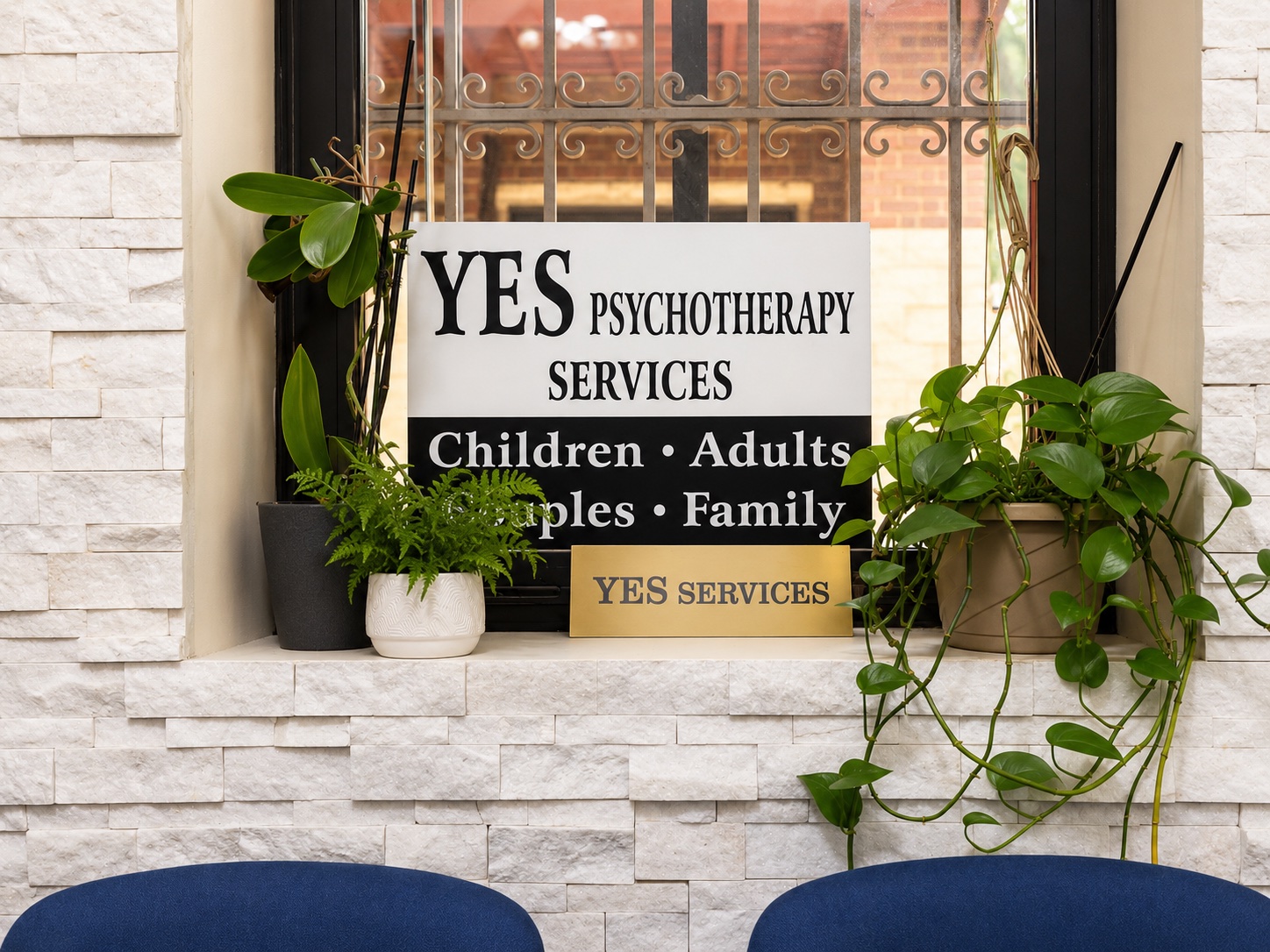 YES Psychotherapy Services sign in the clinic window surrounded by plants